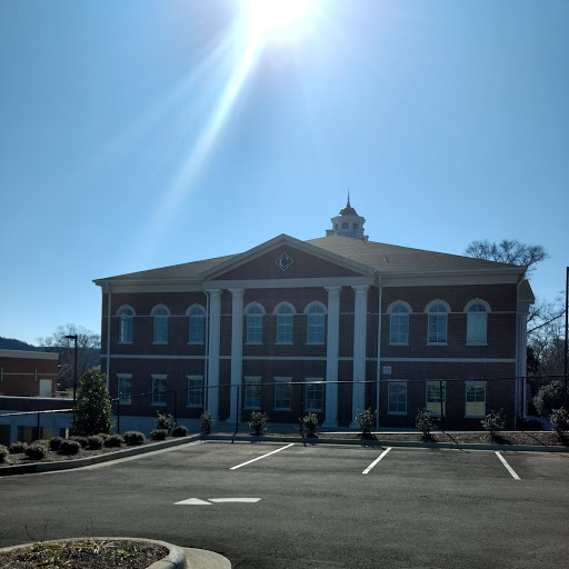 Brick building with white columns and a sunny day.