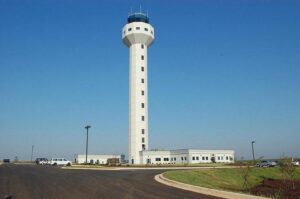 Tall white airport control tower.