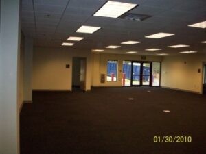 Empty office with black carpet and large windows.