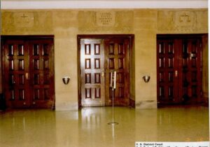 Three wooden doors in a courtroom.