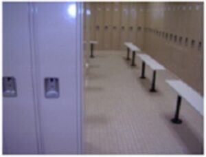 White lockers and benches in a locker room.