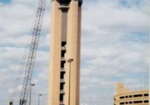 A large building with a tower and some cranes